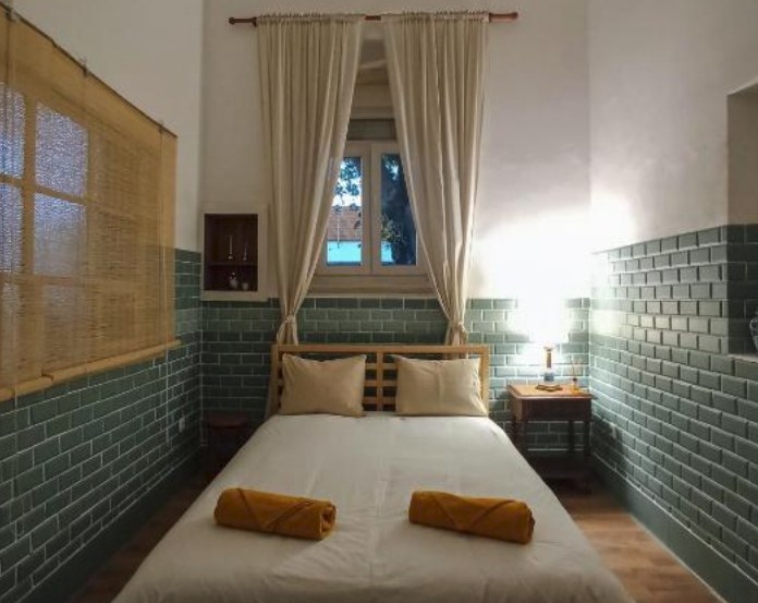 A monthly room with green tiles and a double bed